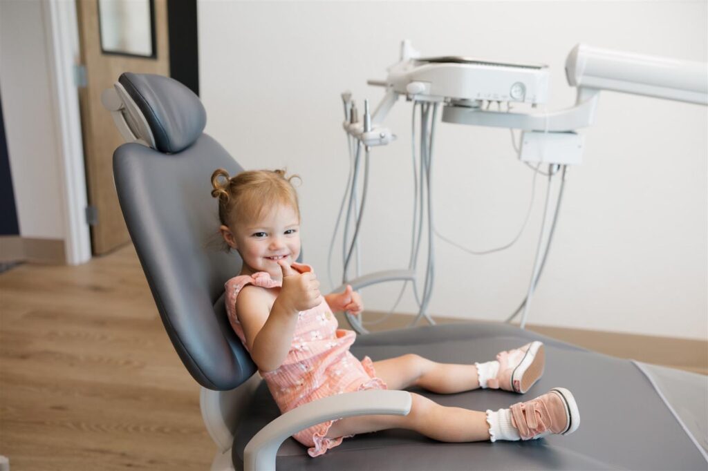 Young child in pink clothing seated comfortably in a gray dental chair at Bookcliff Family Dental in Grand Junction, CO, highlighting the clinic’s welcoming environment and gentle care approach for pediatric patients.