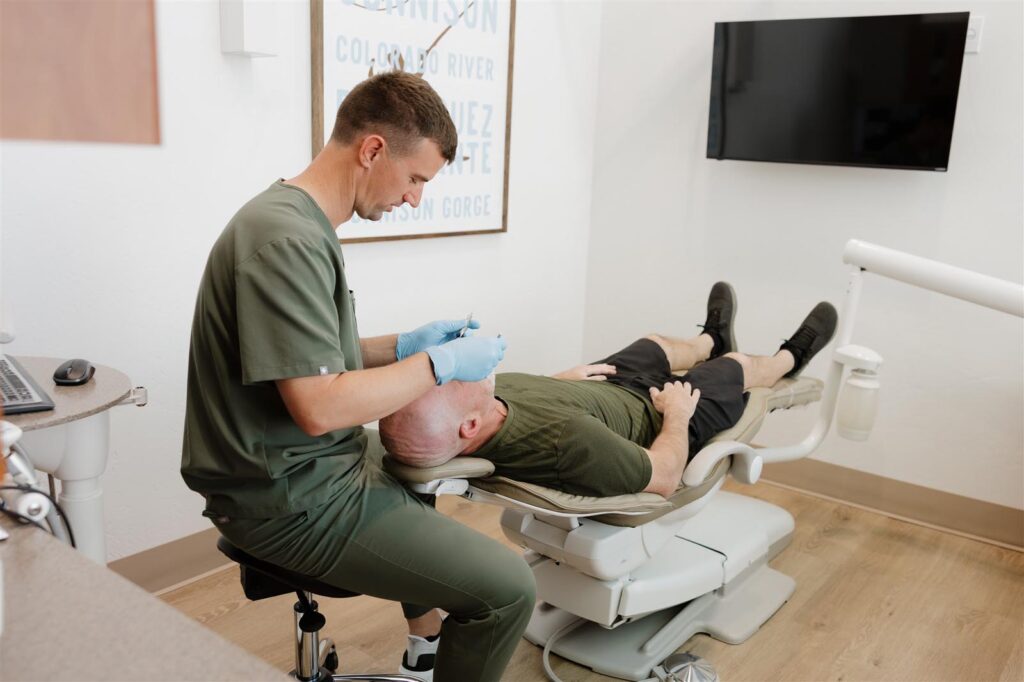 Dental provider at Bookcliff Family Dental in Grand Junction, CO, performing a scalp injection or therapeutic procedure in a treatment room, emphasizing the clinic’s commitment to comprehensive preventative care in a calm, patient-focused setting.